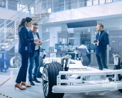automotive-design-engineers-talking-while-working-on-electric-car-chassis-prototype-in-innovation-laboratory-facility-concept-vehicle-frame-includes-2CYTA1R